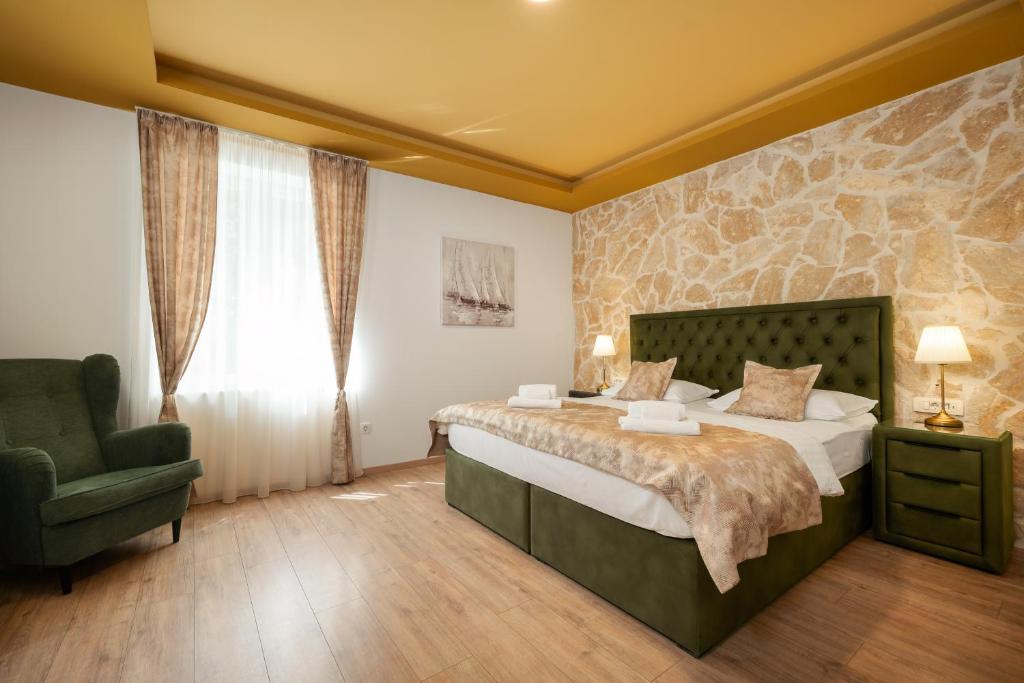 a bedroom with a large bed and a green chair at Luxury Rooms Floramye in Split