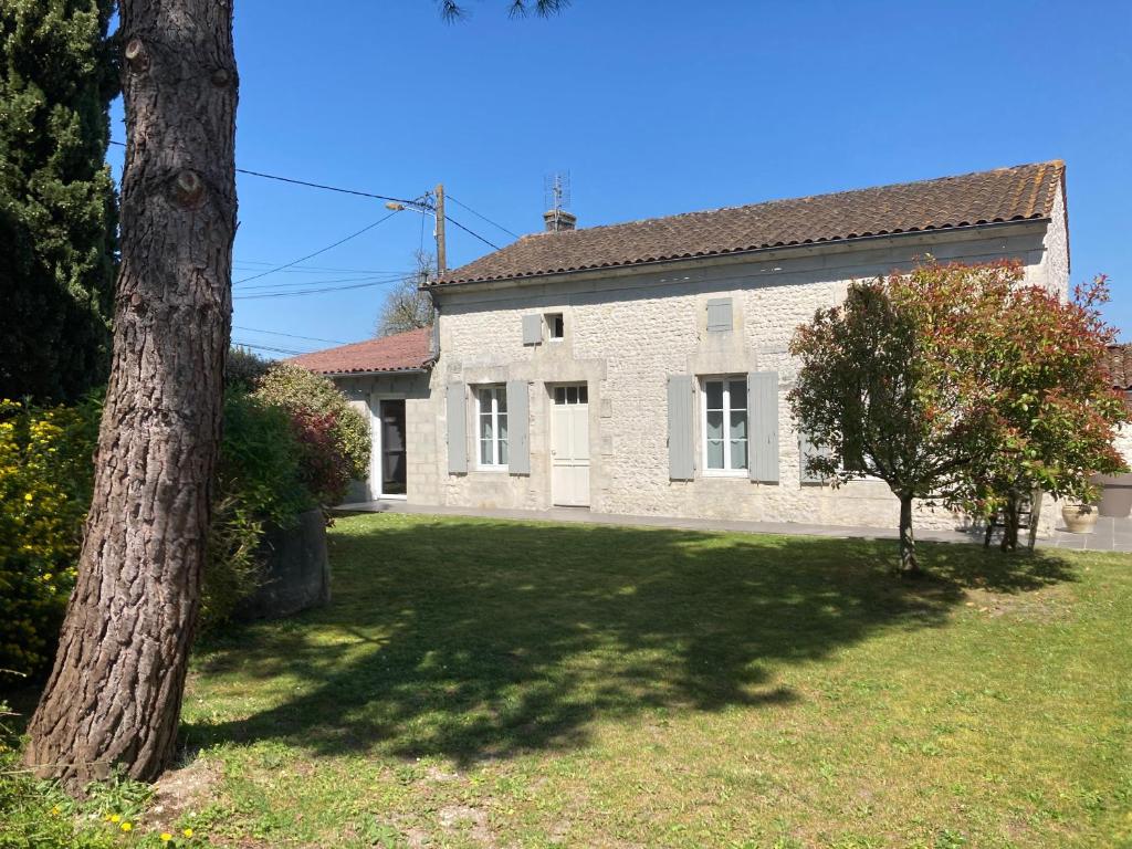 a white brick house with a tree in the yard at Gîte des Vignes in Archiac