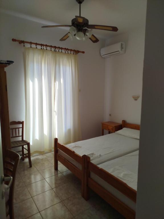 sypialnia z łóżkiem i wentylatorem sufitowym w obiekcie Karagiozos Studios & Apartments w mieście Skopelos