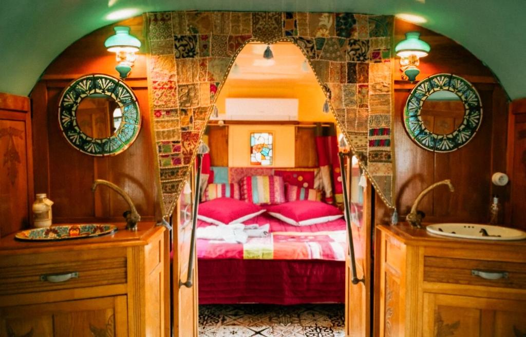 a bedroom with a bed and a sink and mirror at Magnifique Roulotte Bohème 1930 in Mézos