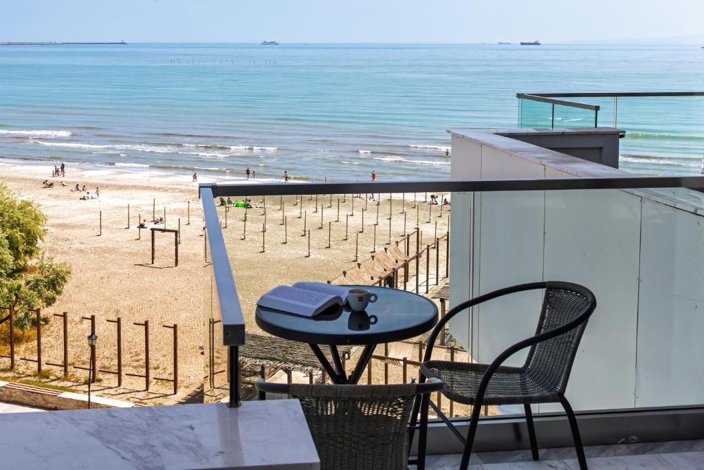 a balcony with a table and chairs and a beach at Riviera - Infinity Pool & Spa Resort in Mamaia