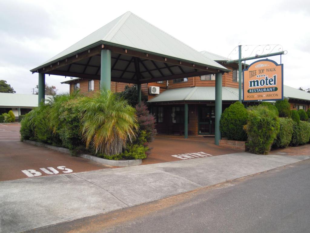 un edificio con un cartel de motel en un estacionamiento en Tree Top Walk Motel en Walpole