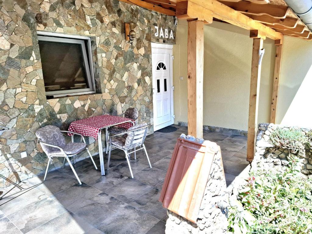 een terras met een tafel en stoelen en een stenen muur bij Apartman Java in Soko Banja