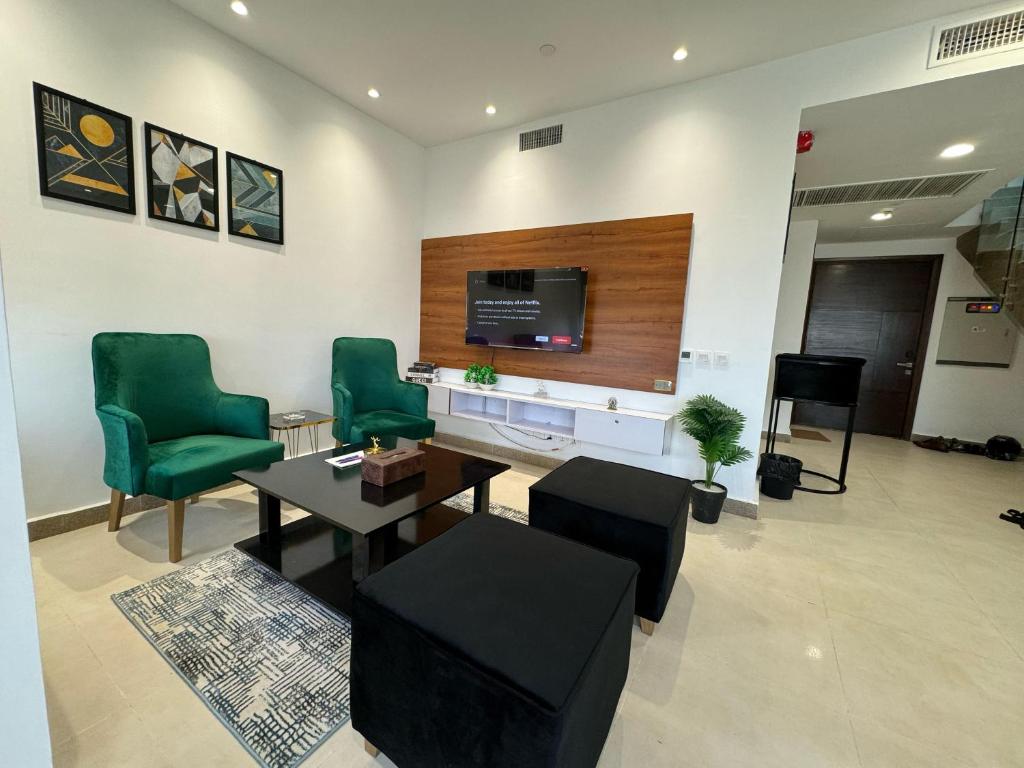 a living room with green chairs and a tv at Penta Square Modern & Luxury Apartments City View DHA Lahore in Lahore