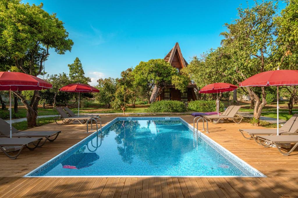 a pool with chairs and umbrellas and a house at Mandarin Bungalow in Alanya