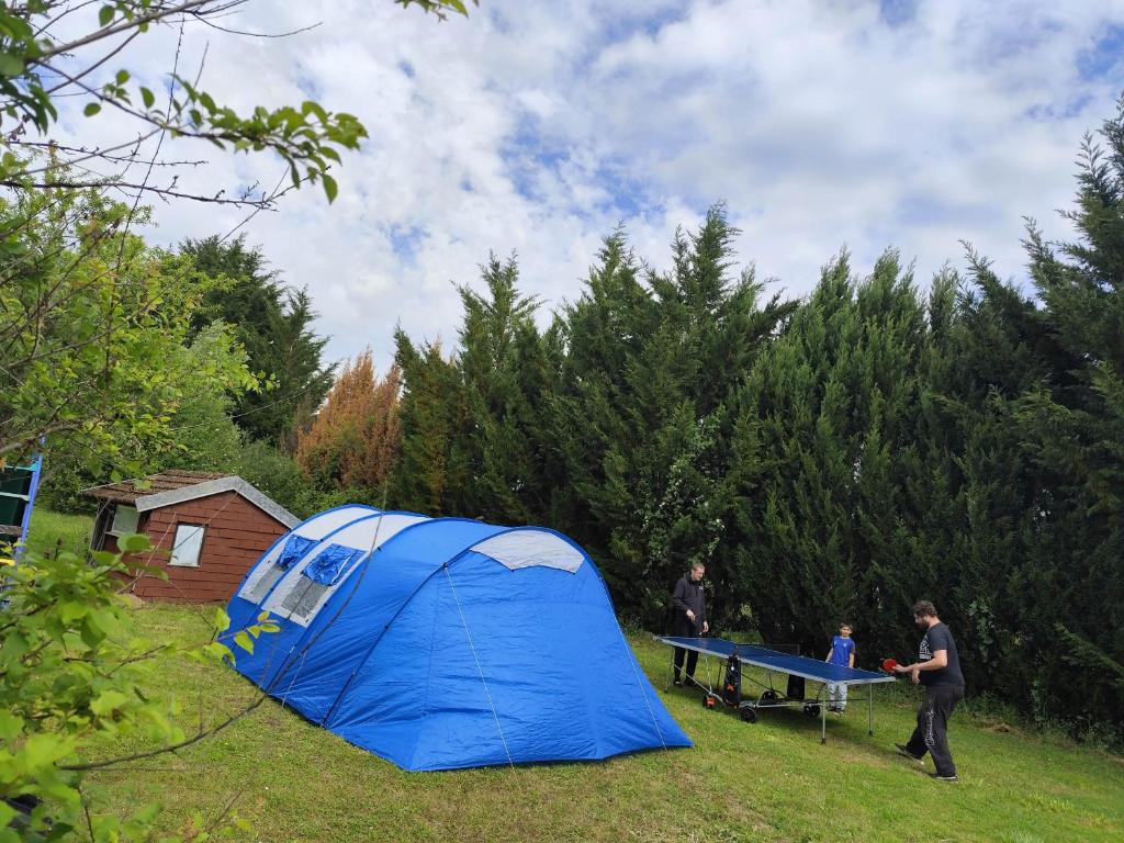 Un groupe de personnes debout à côté d'une tente bleue dans l'établissement Emplacement au bord d'un petit étang, à Chaudenay