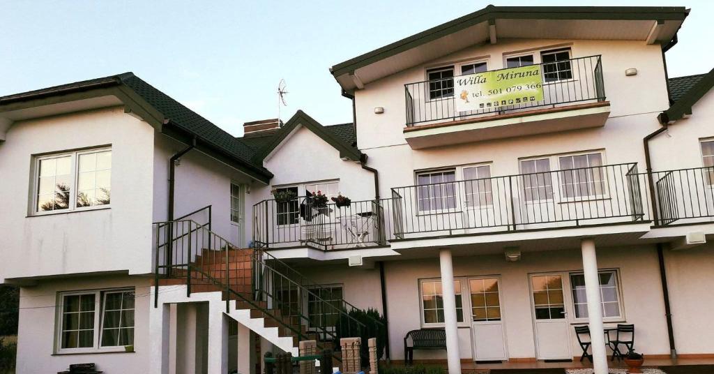 a large white building with balconies and a sign on it at Willa Miruna w Grzybowie in Grzybowo