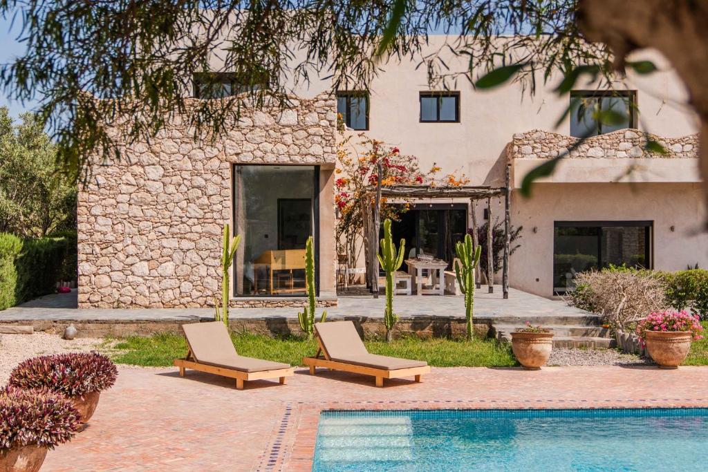 a house with a swimming pool and two lounge chairs at Villa Talya in Ghazoua