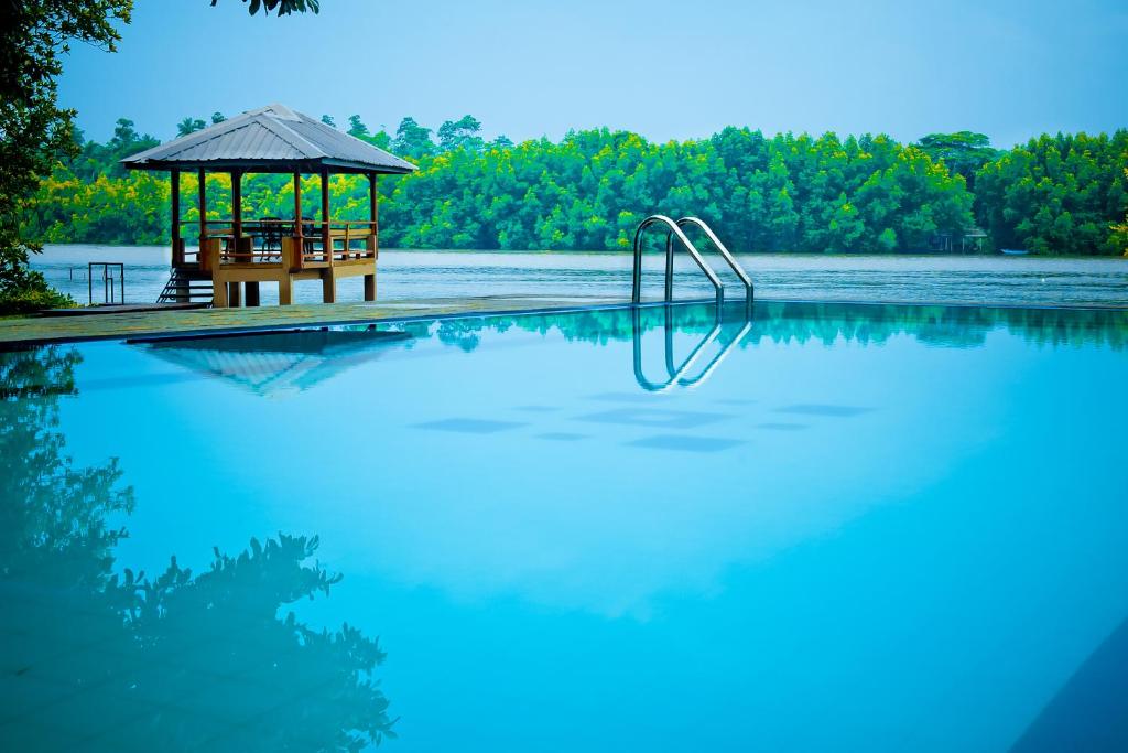 a swimming pool with a gazebo next to a lake at Okvin River Villa in Bentota