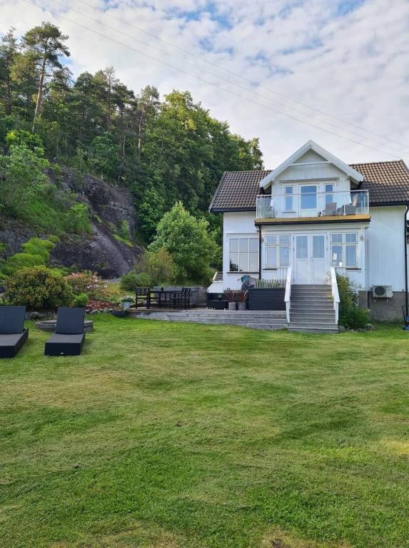 a white house with a yard with chairs at Solheimhuset - feriehus nær Tjøme og VerdensEnde in Tokenes