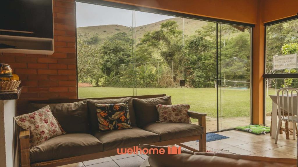 a living room with a couch and a large window at Sitio em Teresópolis com Piscina e Churrasqueira in Teresópolis
