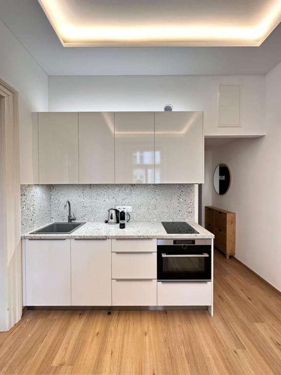 une cuisine avec des armoires blanches et un évier dans l'établissement Old Town Prague Apartment, à Prague