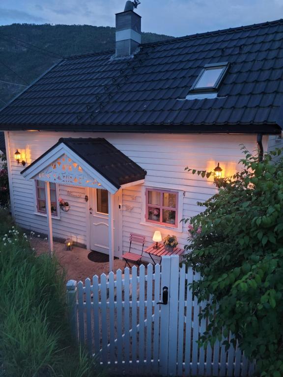 una casa blanca con una valla delante en Sjarmerende perle med utsikt mot fjorden, en Sogndal