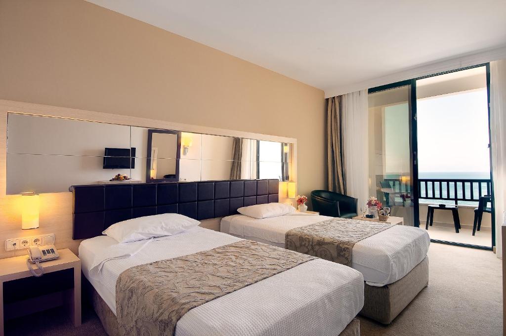 a hotel room with two beds and a balcony at Golden Lotus Hotel in Kemer