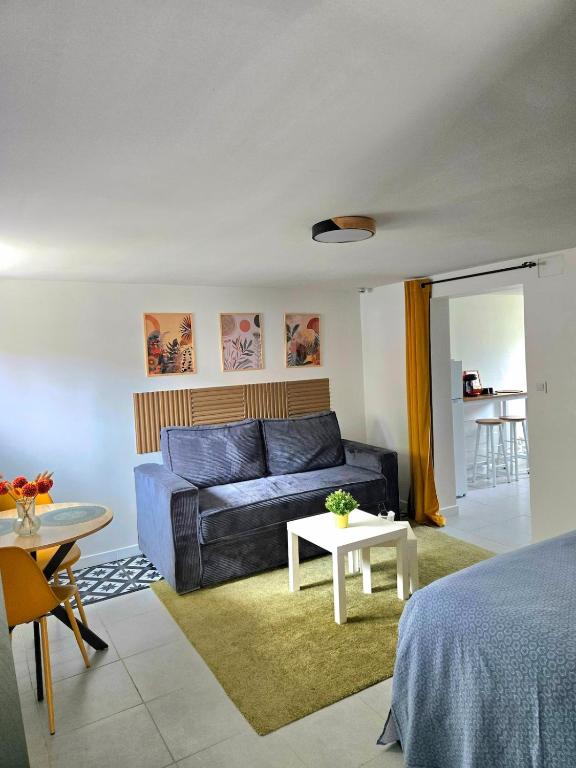 a living room with a blue couch and a table at Grand studio cosy proche Paris in Épinay-sur-Seine