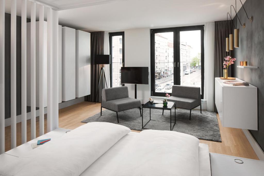 a bedroom with a white bed and two chairs at AMANO HOME Apartments in Berlin