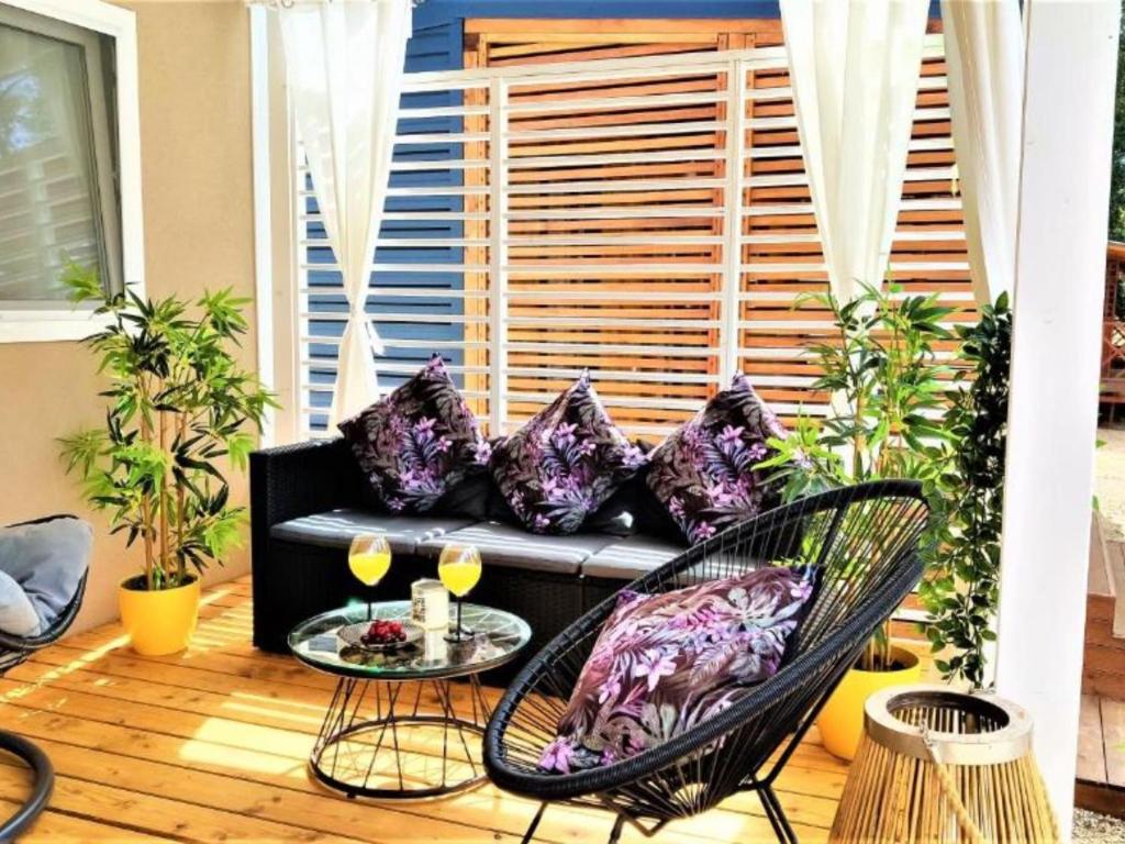 Un patio con un sofá negro, una mesa y sillas. en Mobile Home Nensi Two bedroom, en Biograd na Moru
