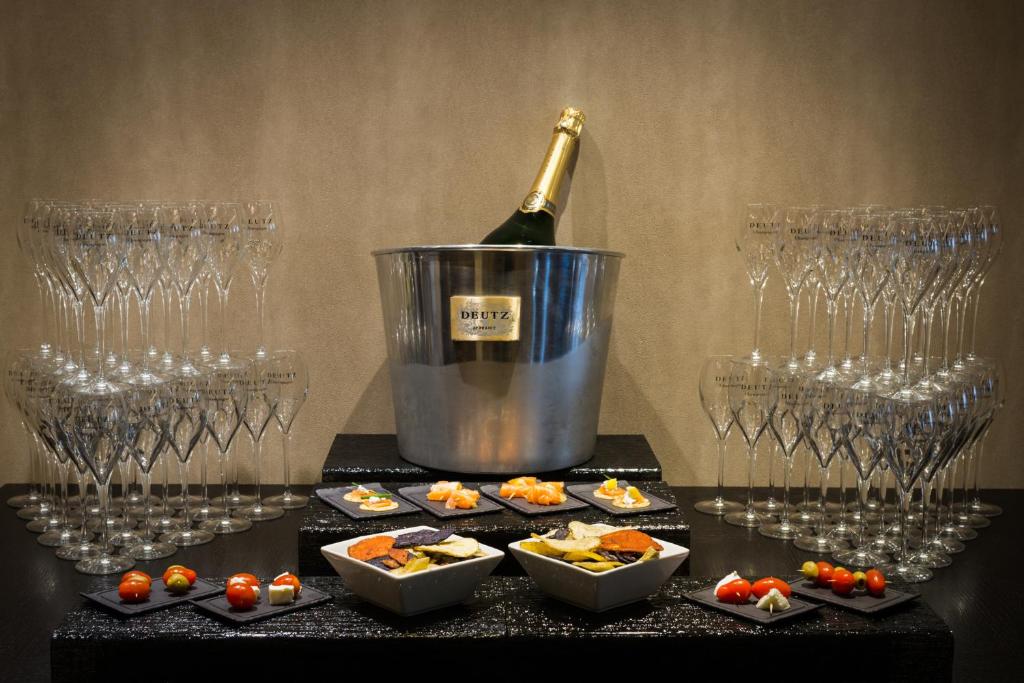 a bottle of wine in a bucket next to wine glasses at Hôtel La Bourdonnais by Inwood Hotels in Paris