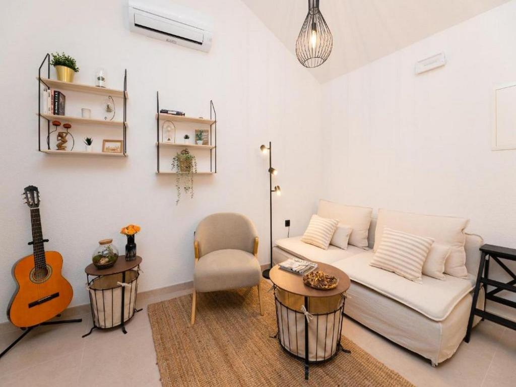 ein Wohnzimmer mit einem weißen Sofa und einer Gitarre in der Unterkunft Villa ADRIANA - Two bedroom Villa with swimming pool in Nerežišće