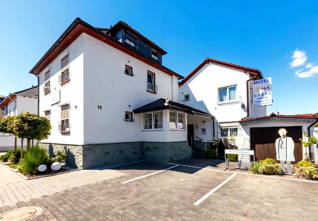 a large white building with a parking lot at Gasper Business & Garden Hotel in Raunheim