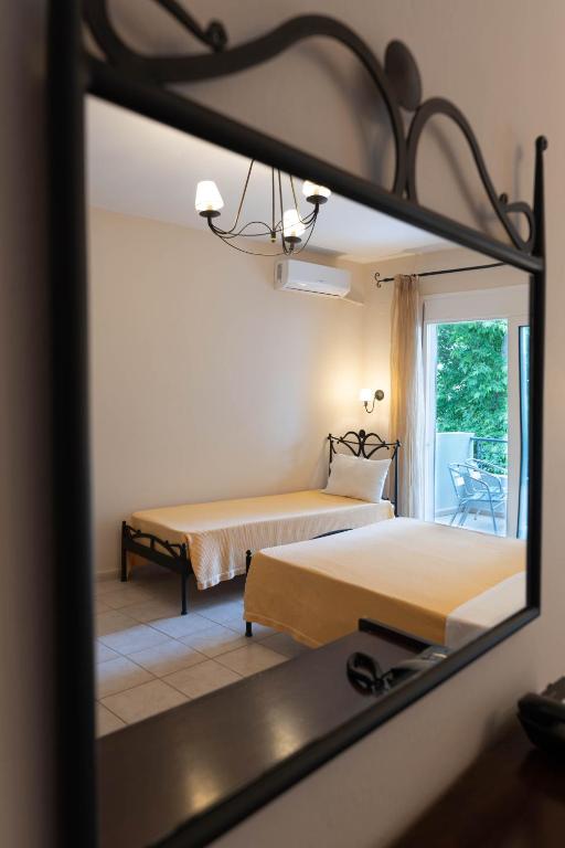 a reflection of a bedroom with two beds in a mirror at Kipos Resort in Nea Peramos