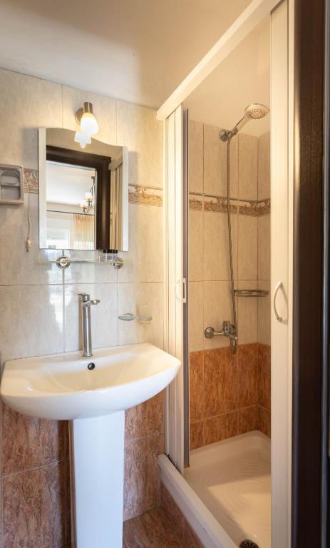 a bathroom with a sink and a shower at Kipos Resort in Nea Peramos