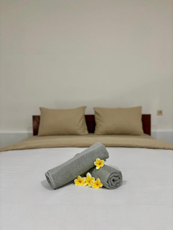 a bed with a towel and flowers on it at Dimas Cottage in Senaru