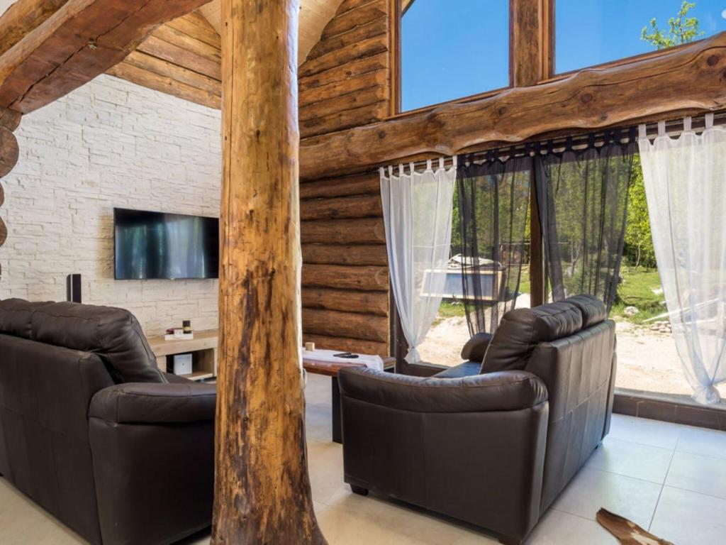 a living room with leather furniture and large windows at Holiday Home Elizabeta in Slunj