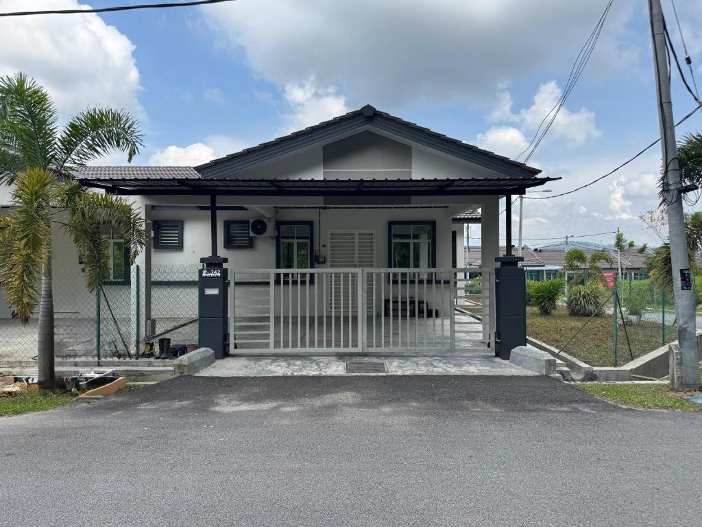 a small white house with a gate at Homestay D BBSE in Simpang Empat