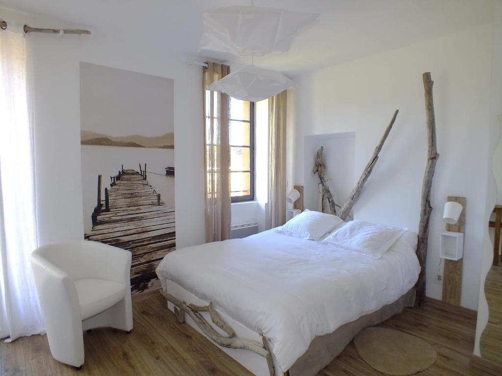 - une chambre avec un lit blanc et une chaise blanche dans l'établissement La Maison de la Tour, à La Tour