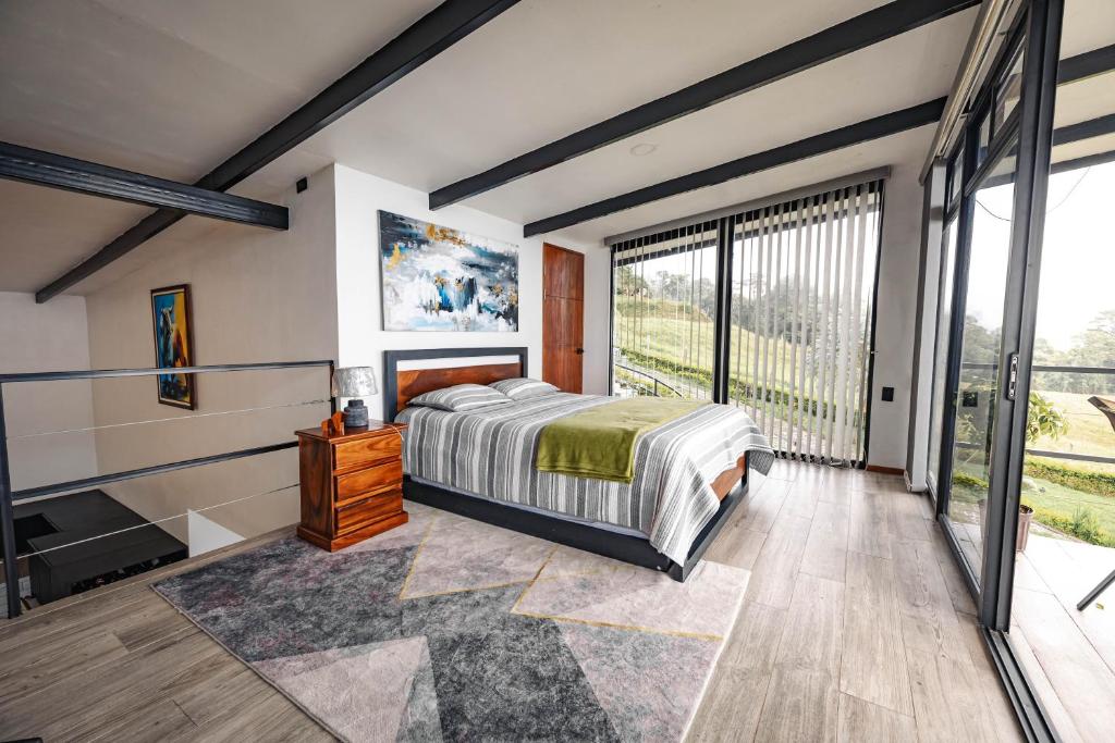 a bedroom with a bed and a large window at Loft con hermosas vistas y Volcán Turrialba in Turrialba