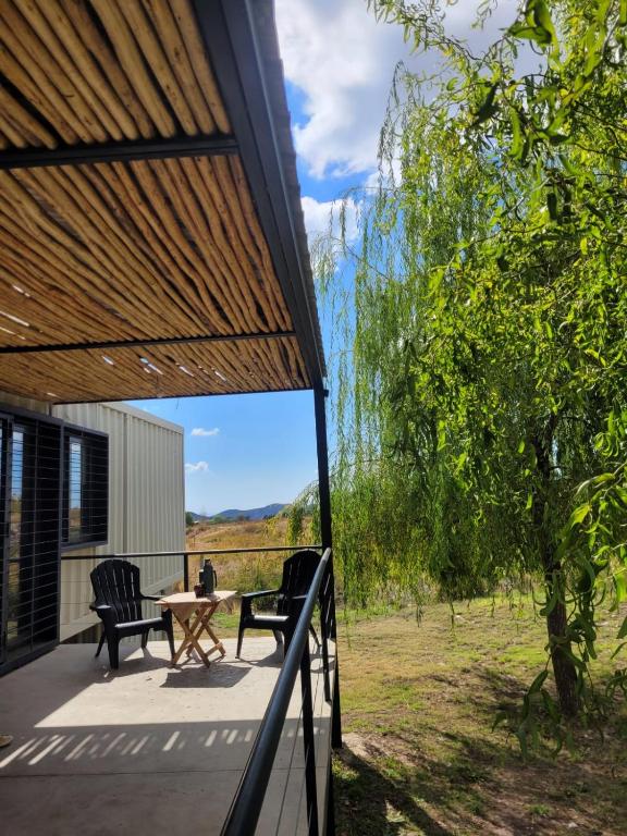 a view from the porch of a house with two chairs and a table at El Contenedor in Tunuyán