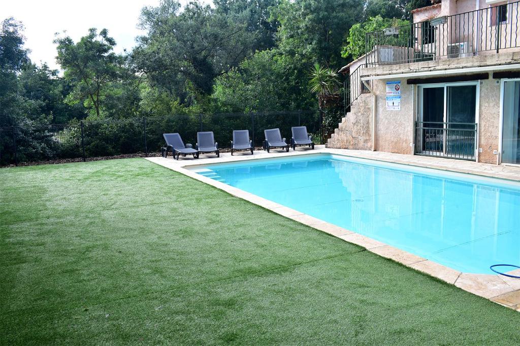 einen Pool mit zwei Stühlen und einen Rasenplatz in der Unterkunft F4 MimiPinson 1er étage Rabinon lac riviere VAR in Le Muy