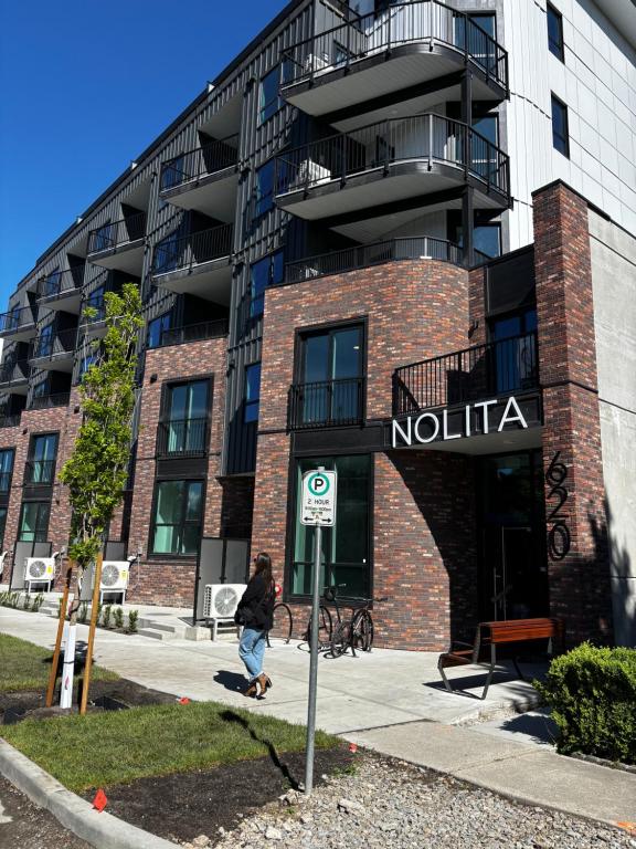 a person walking in front of a building at Brand new suite downtown Kelowna - walk everywhere! in Kelowna
