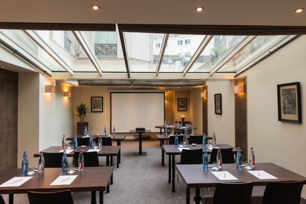 a conference room with tables and chairs and a whiteboard at Hôtel La Bourdonnais by Inwood Hotels in Paris