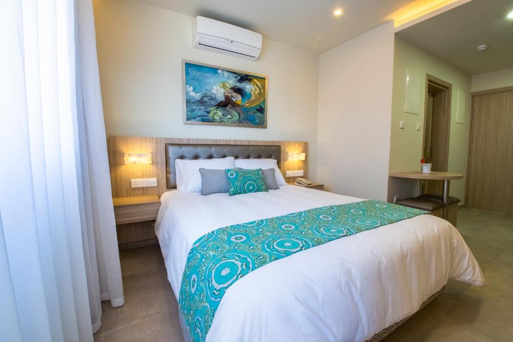 a bedroom with a large bed with a blue and white comforter at Zodiac Hotel Apartments in Larnaca