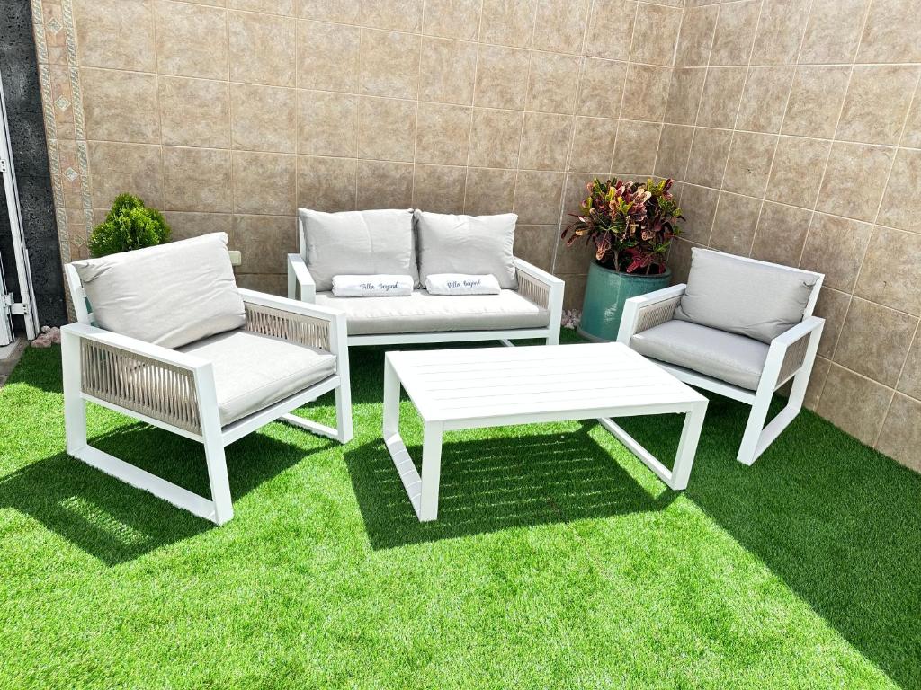 three chairs and a table and a table and chairs on grass at Serenity Villa Lanzarote by Beyond in San Bartolomé