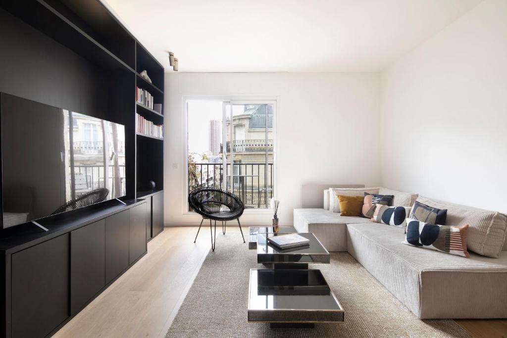 un salon avec un canapé et une télévision dans l'établissement Bright & Chic apartment Near Porte Maillot - 4P, à Neuilly-sur-Seine