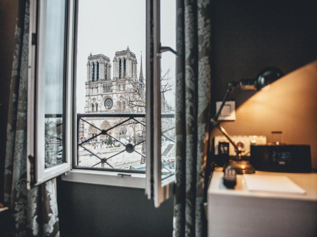 
a large window with a view of a city at Hotel Le Notre Dame Saint Michel in Paris
