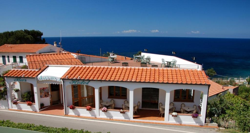 ein weißes Haus mit orangefarbenem Dach und Meer in der Unterkunft Hotel Aurora in Chiessi