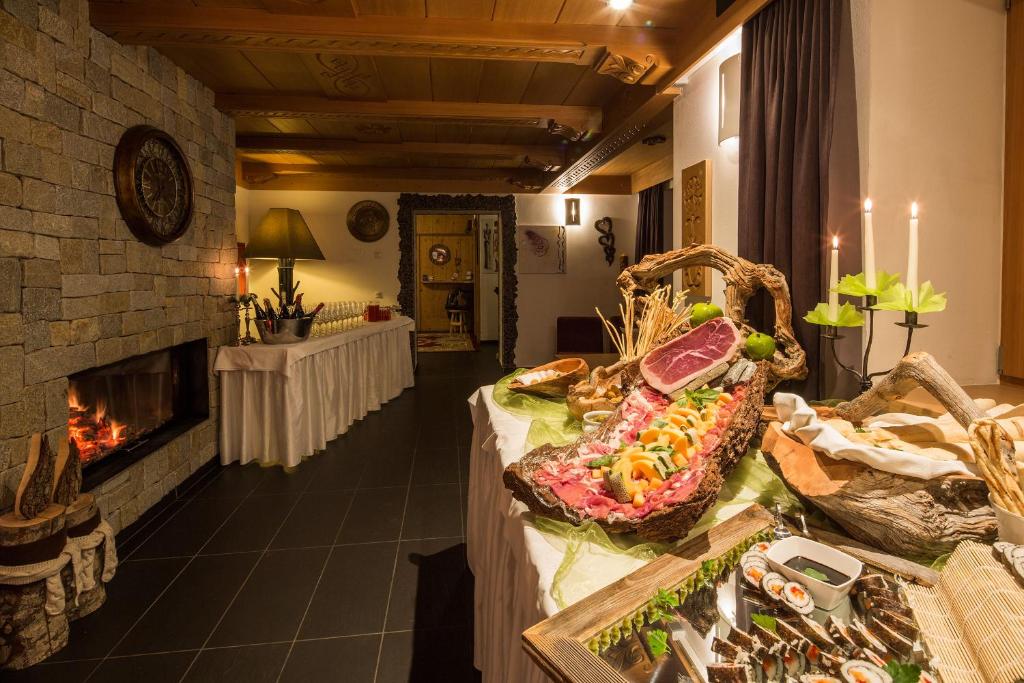 a room with a fireplace and a table with food at Hotel Rezia in La Villa