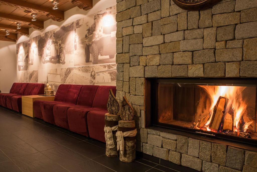 a fireplace in a room with a red couch at Hotel Rezia in La Villa