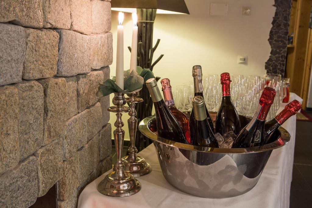 a bucket of wine bottles on a table with a candle at Hotel Rezia in La Villa