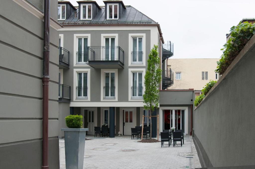 un edificio blanco con un patio con mesas y sillas en Hotel im Hof, en Múnich