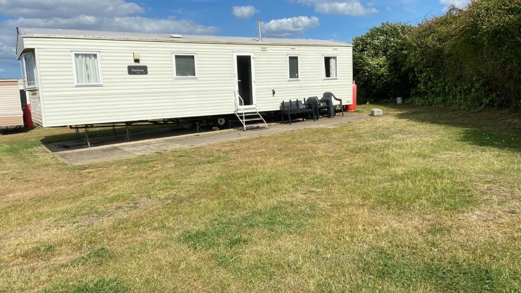 a white trailer with chairs in a yard at The Link Inn in Allhallows
