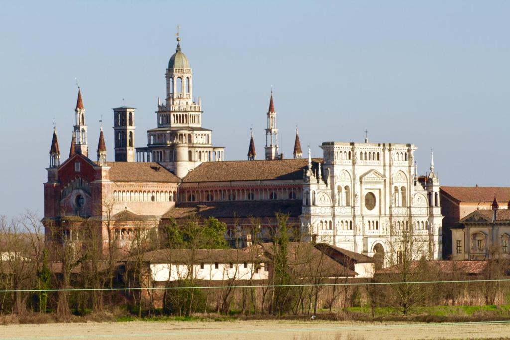 un grande edificio bianco con torri sopra di Hotel Monumento a Certosa di Pavia