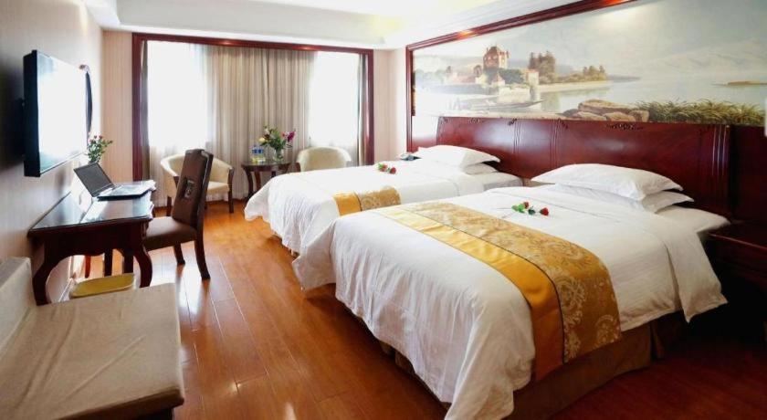 ein Hotelzimmer mit zwei Betten und einem Schreibtisch in der Unterkunft GreenTree Inn Shanghai Waigaoqiao Free Trade Zone Express Hotel in Shanghai