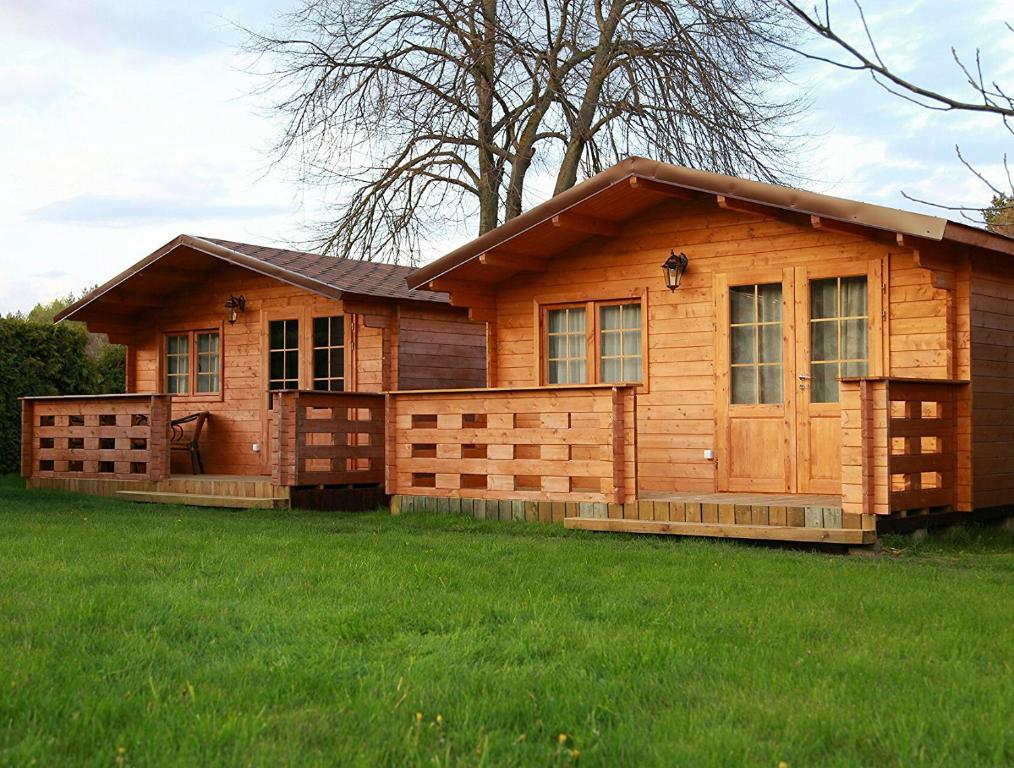 a log cabin with a green lawn in front of it at Nemirsetos Nameliai in Palanga