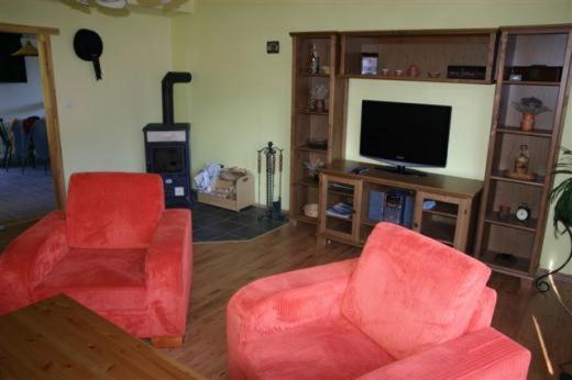 a living room with two red chairs and a television at Pension Strnad in Velká Úpa