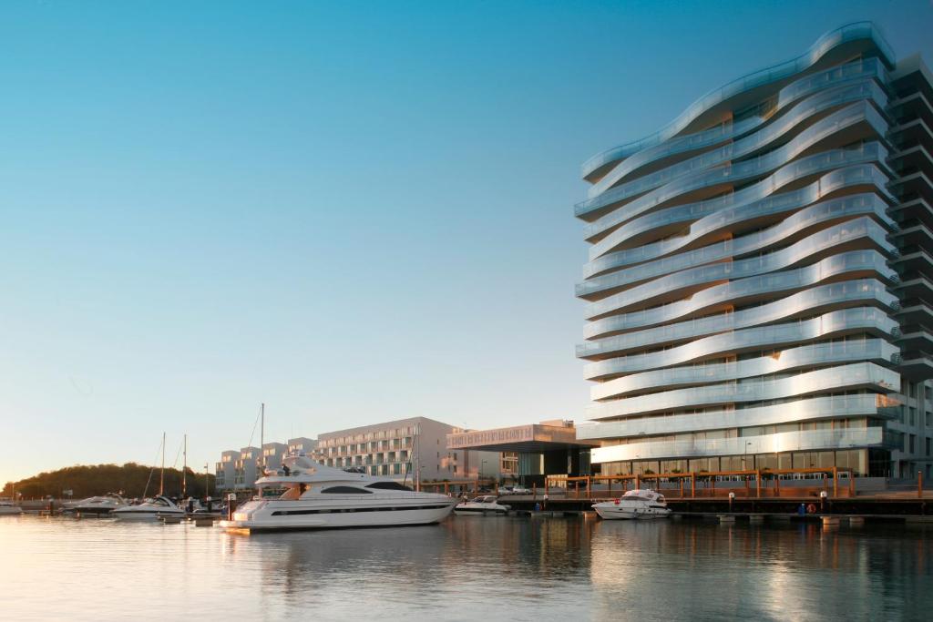 un bateau dans l'eau à côté d'un bâtiment dans l'établissement Troia Design Hotel, à Tróia